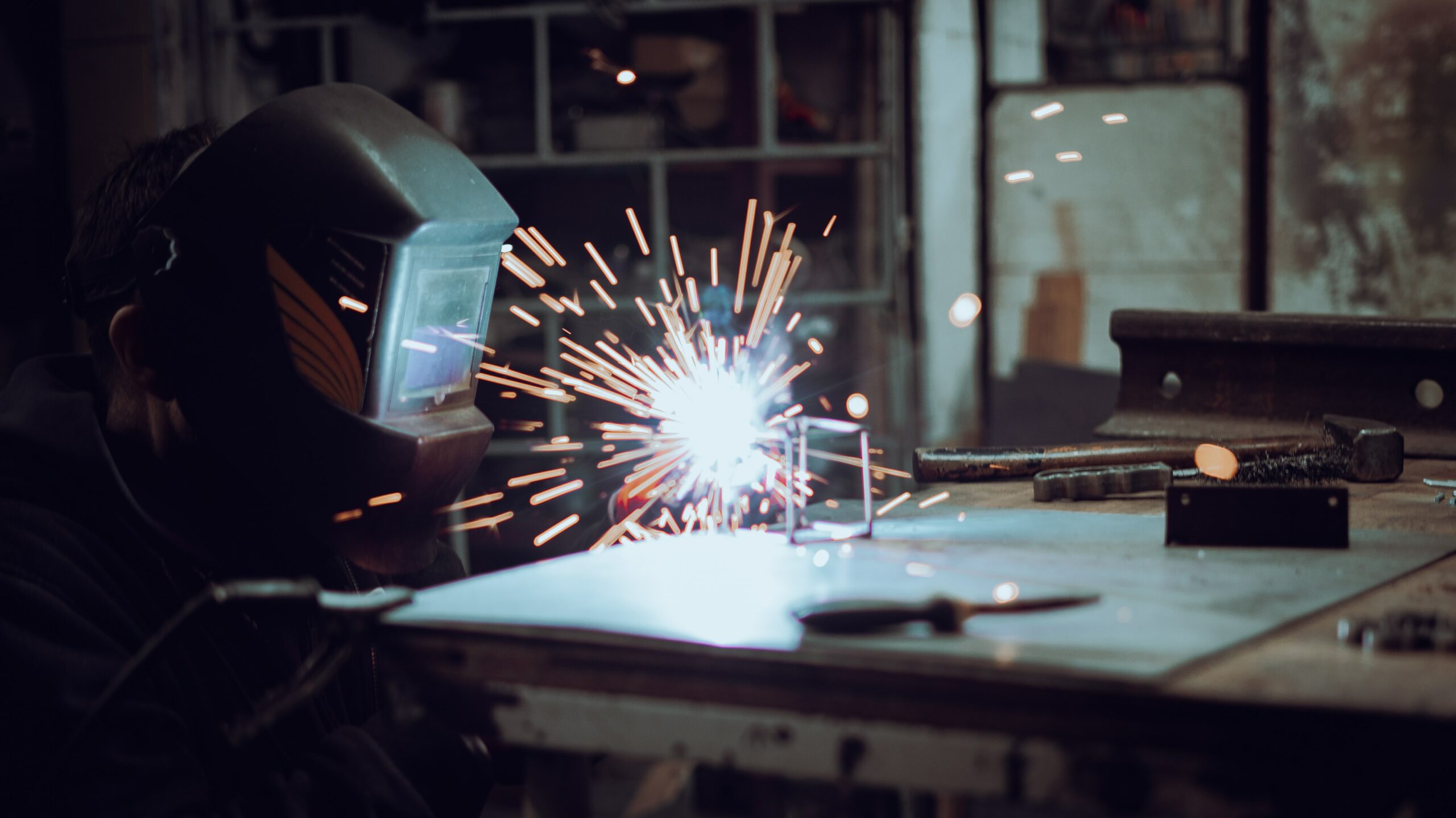 Person soldering metal in a dark environment.