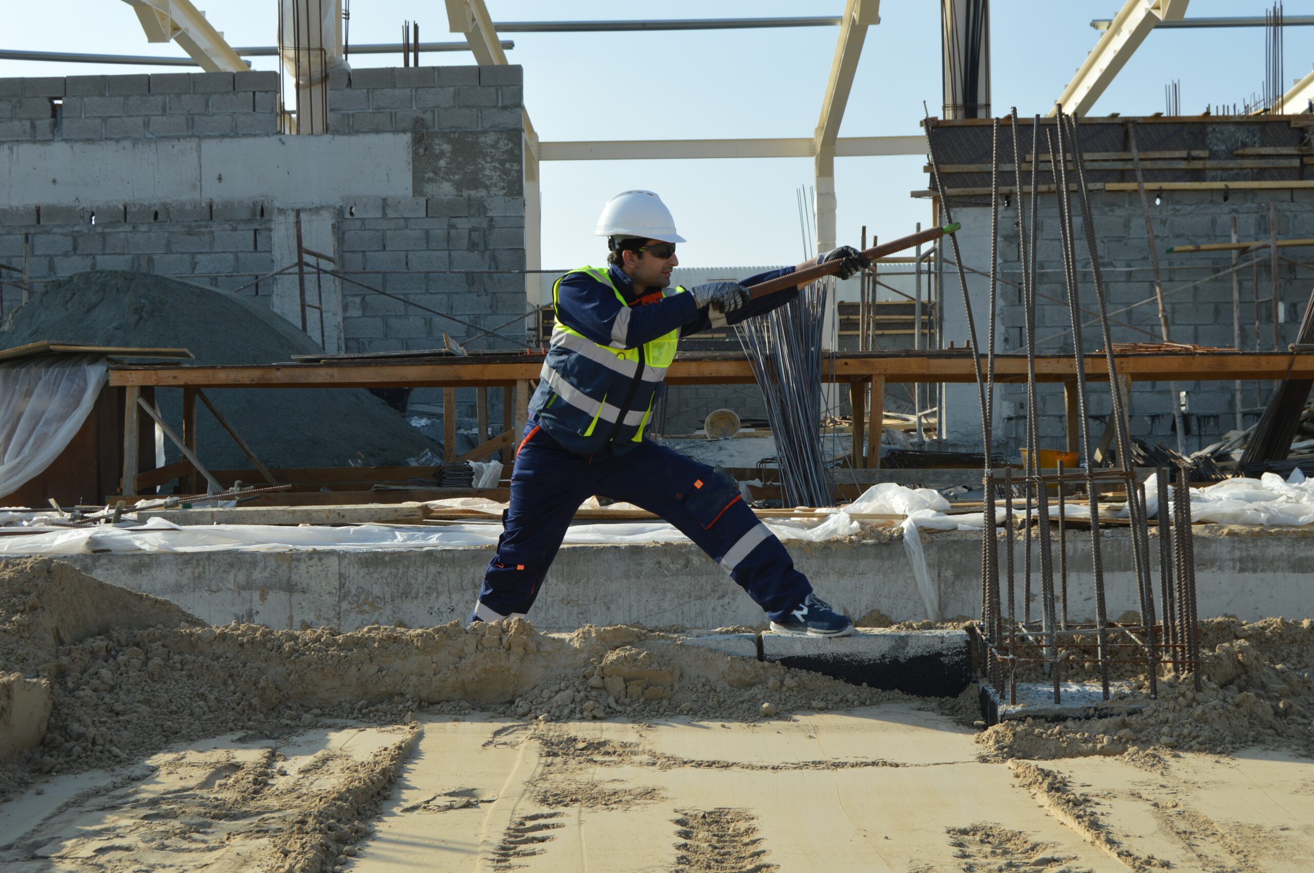 Man working in a construction area prying a metal stud.